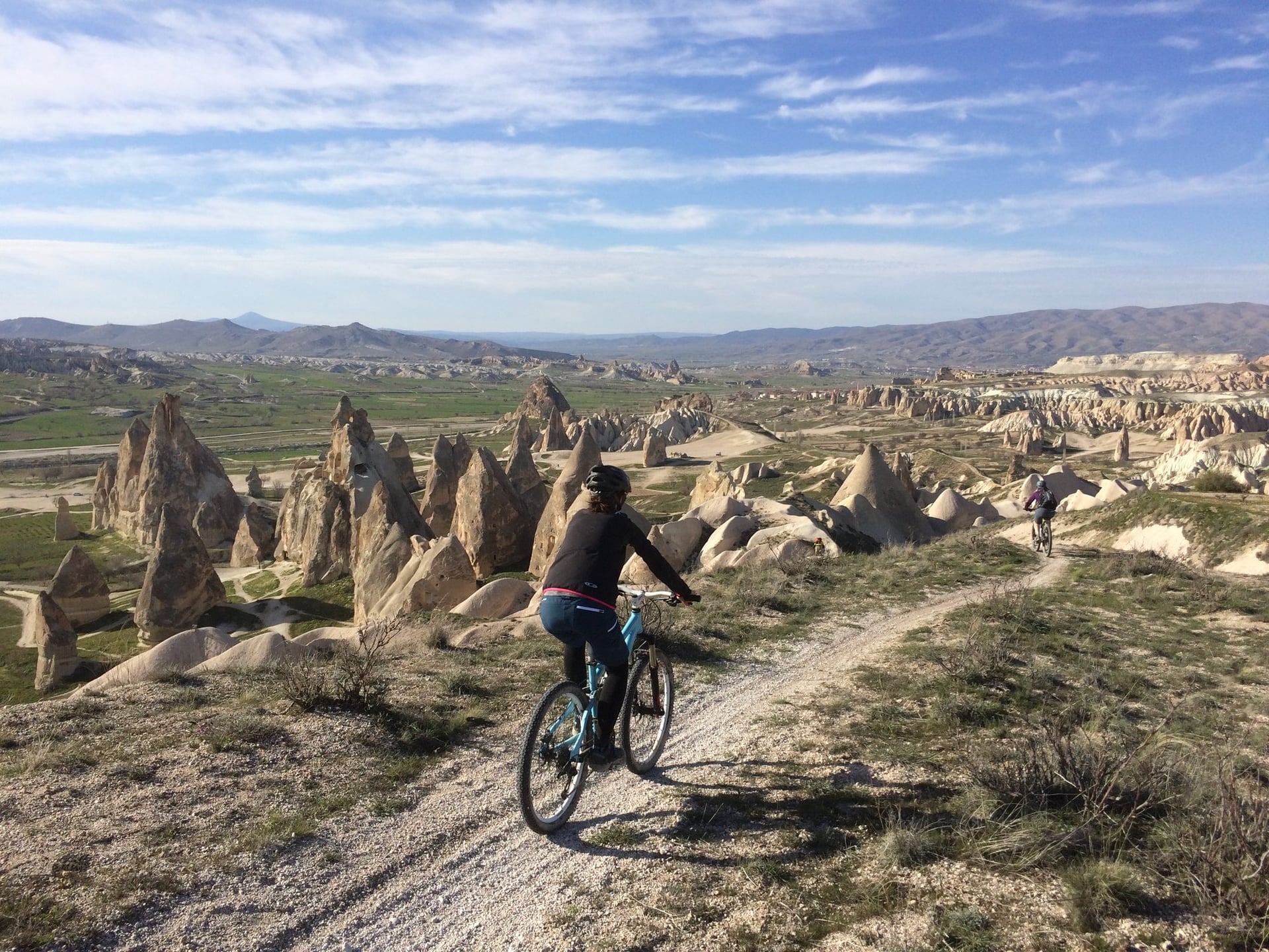 Cyclist riding a dirt trail among tall fairy chimney rock formations in Cappadocia
