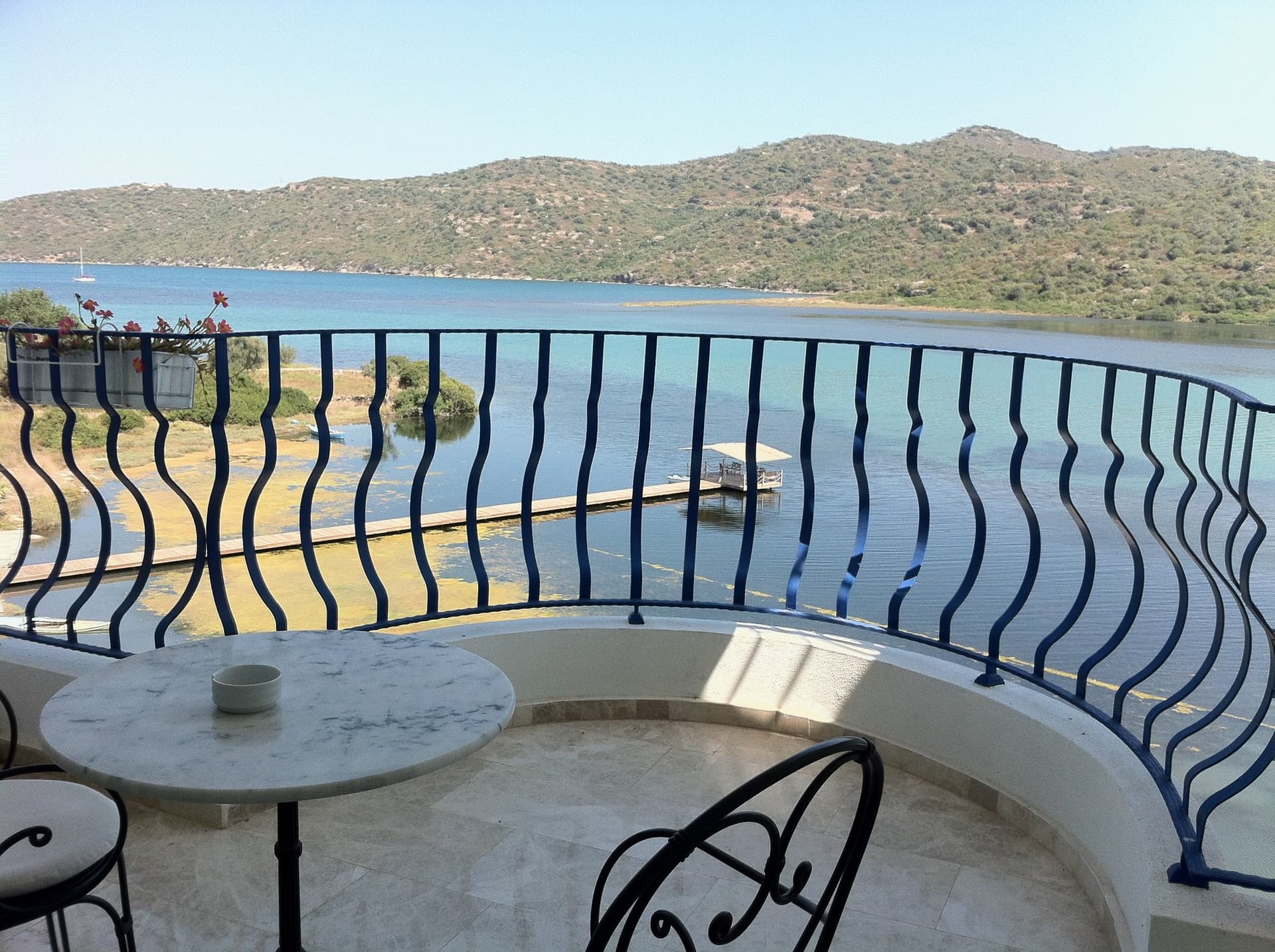 Balcony with wrought-iron railing overlooking a bay and hills