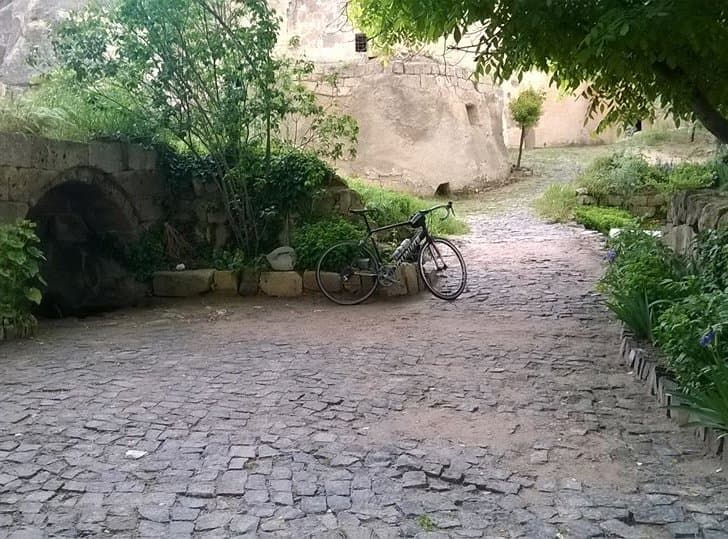Bicycle parked on a cobblestone path leading toward a stone archway