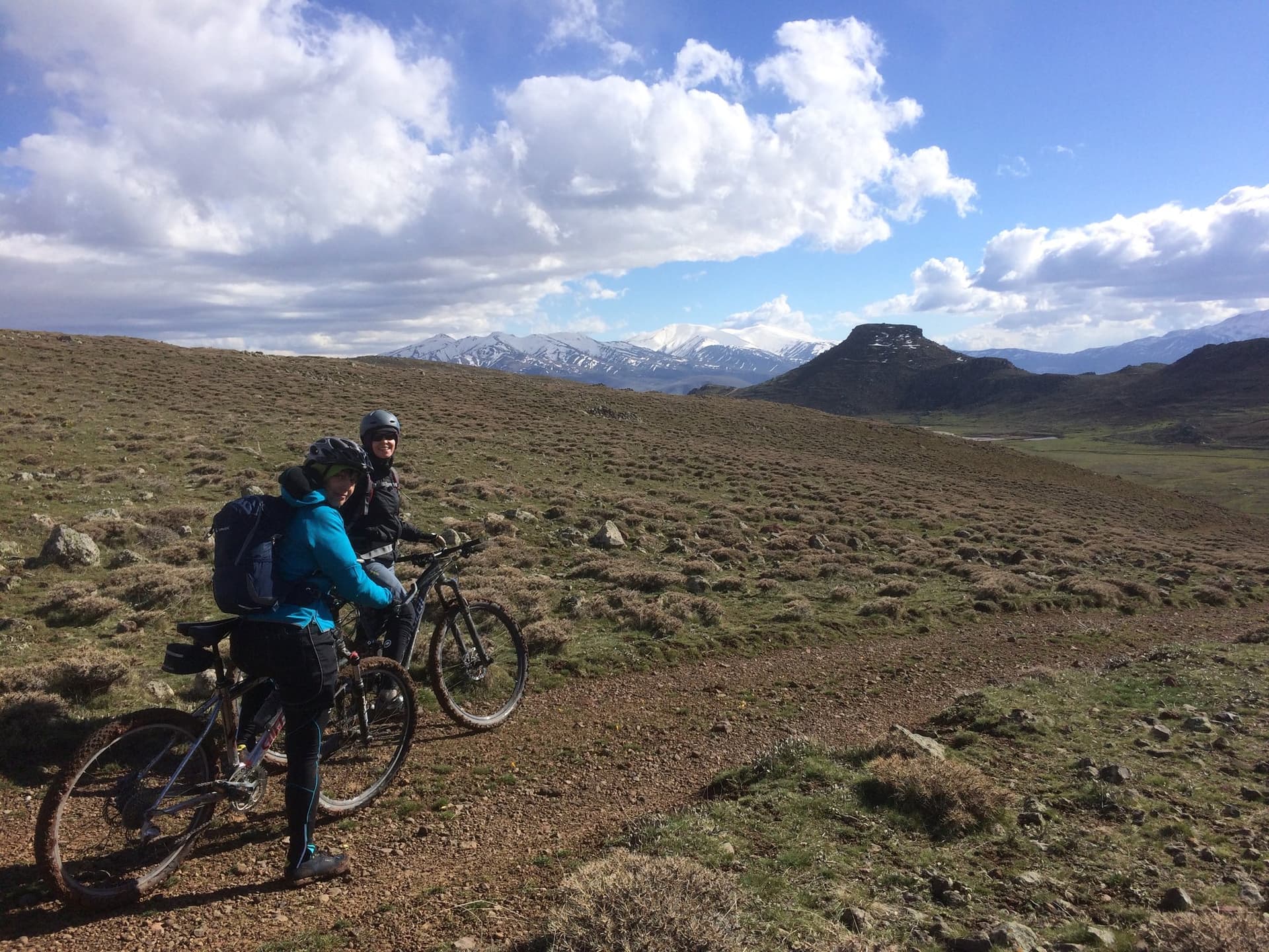 Bikepackers crossing open steppe with snow-capped mountains on the Cappadocia horizon