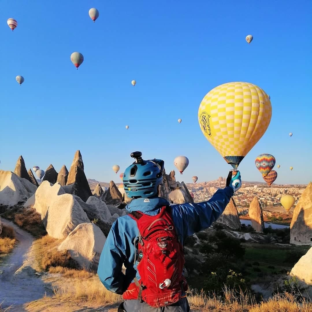 Mountain biker overlooking hot air balloons and fairy chimneys in Cappadocia, Turkey