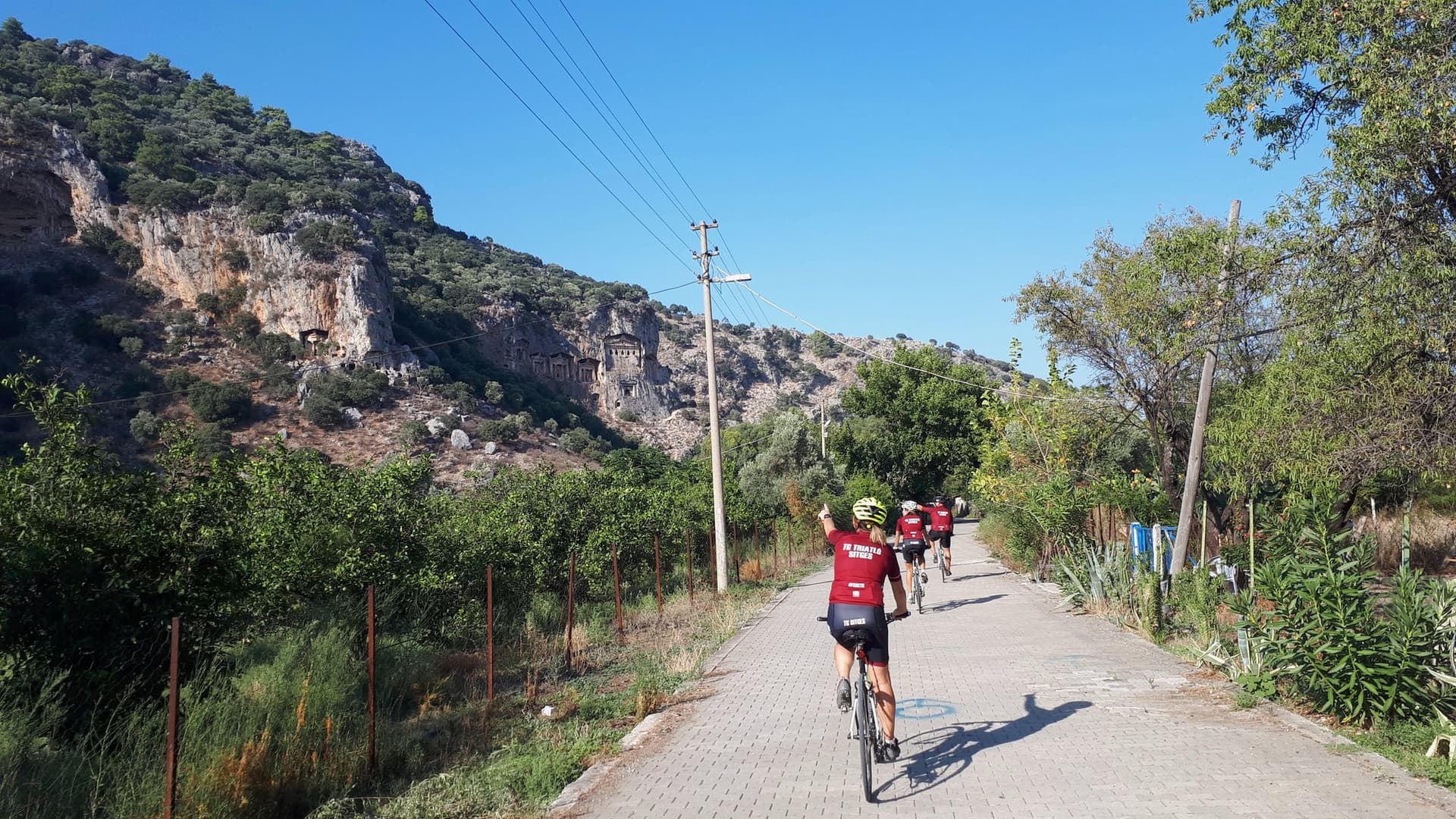 Cyclists riding past ancient rock-cut tombs on the Aegean Coast Road Bike Tour in Turkey