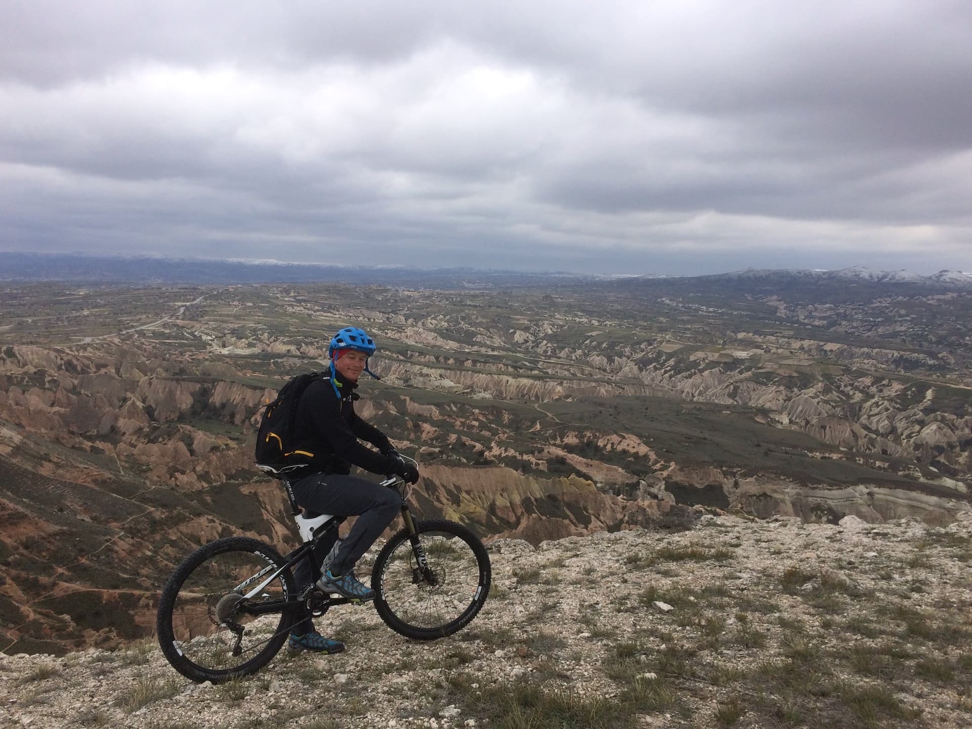 Cyclist pausing above an eroded red-rock valley in Cappadocia