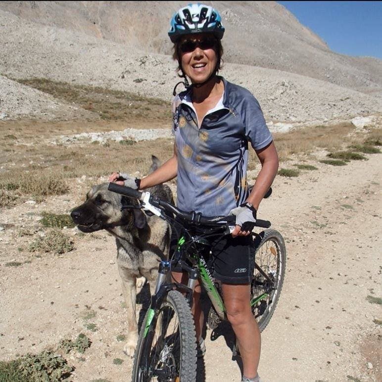Cyclist pausing with a shepherd dog on a rocky mountain trail in the Taurus Mountains