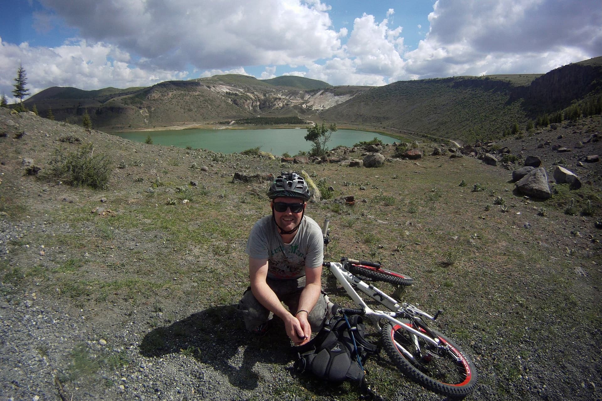 Cyclist resting beside their bike near a volcanic crater lake in Cappadocia