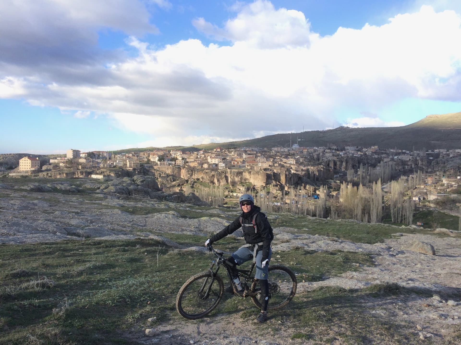 Cyclist riding above a hillside town of weathered rock dwellings