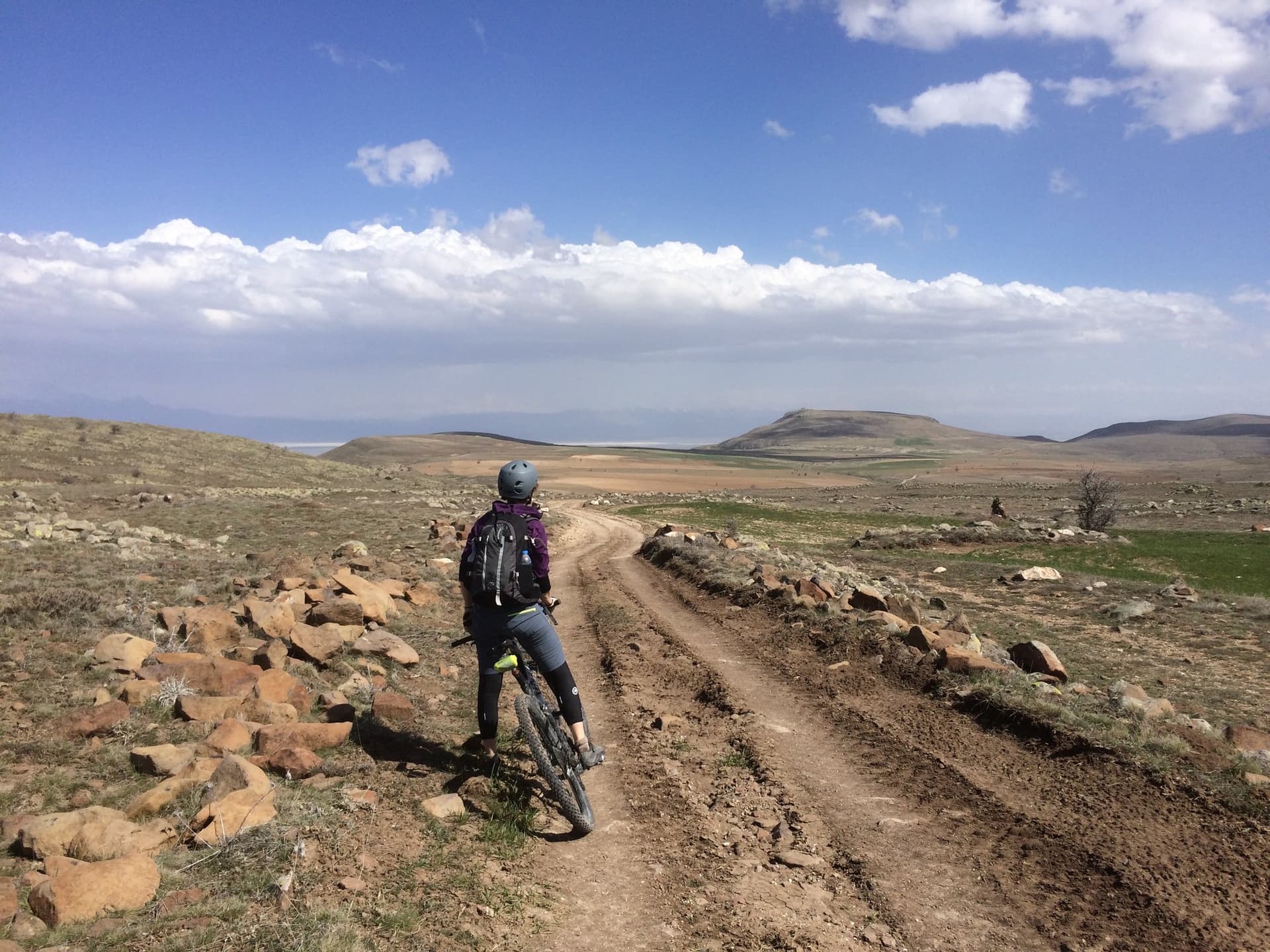 Cyclist riding a muddy dirt track across an open Cappadocia landscape