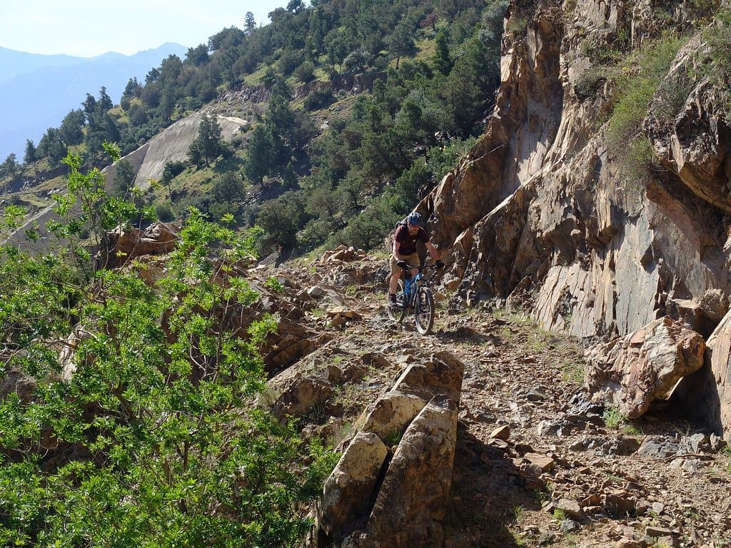 Cyclist riding a narrow rocky ridge trail in the Atlas Mountains, Morocco