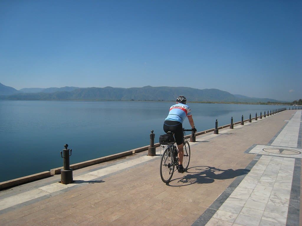 Cyclist riding along a paved lakeside promenade in the Atlas Mountains, Morocco