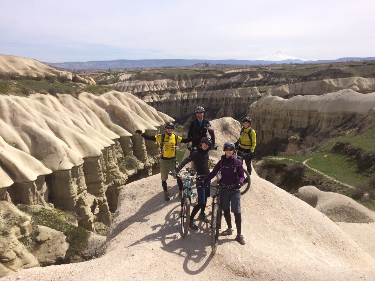 Cyclists with their bikes at the edge of an eroded canyon in Cappadocia
