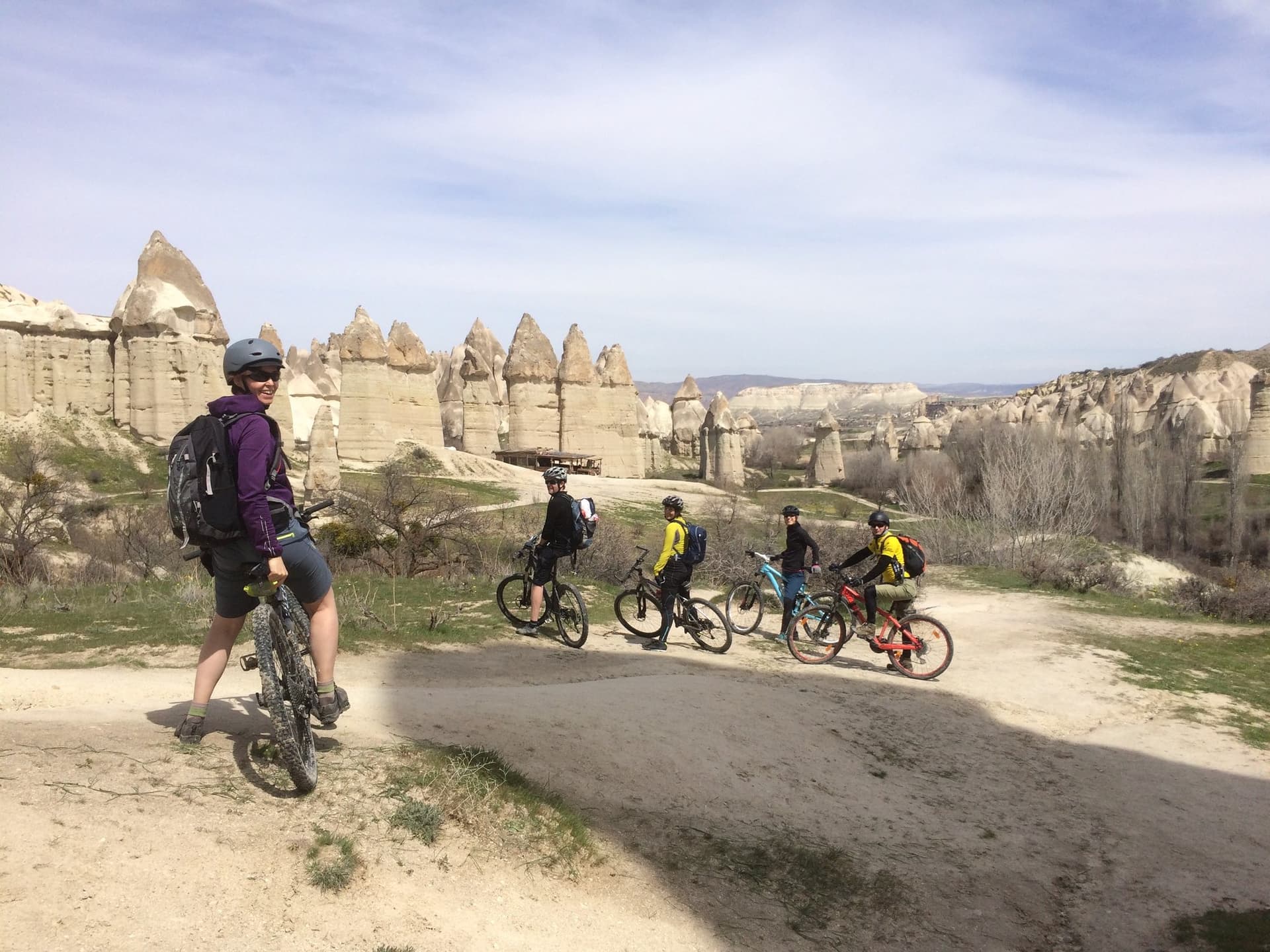 Cyclists with their bikes gathered among fairy chimney formations in Cappadocia
