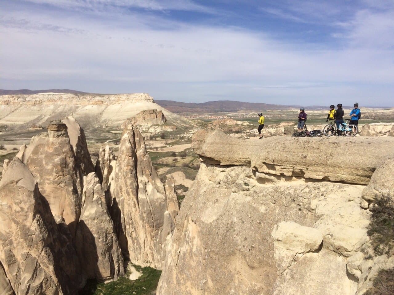 Cyclists on a rocky ridge overlooking jagged rock pinnacles in Cappadocia