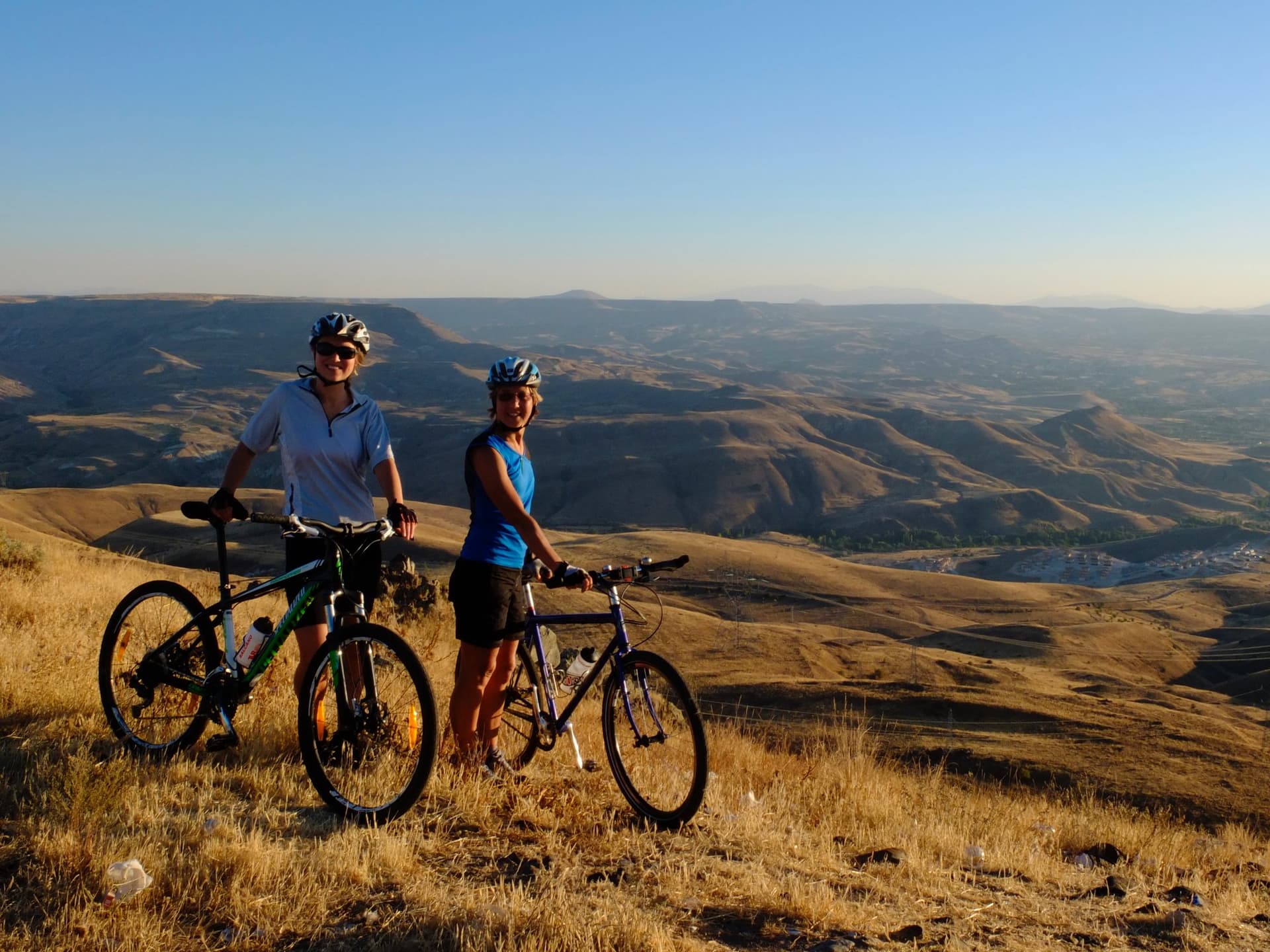 Two cyclists standing with their bikes overlooking a canyon in Cappadocia