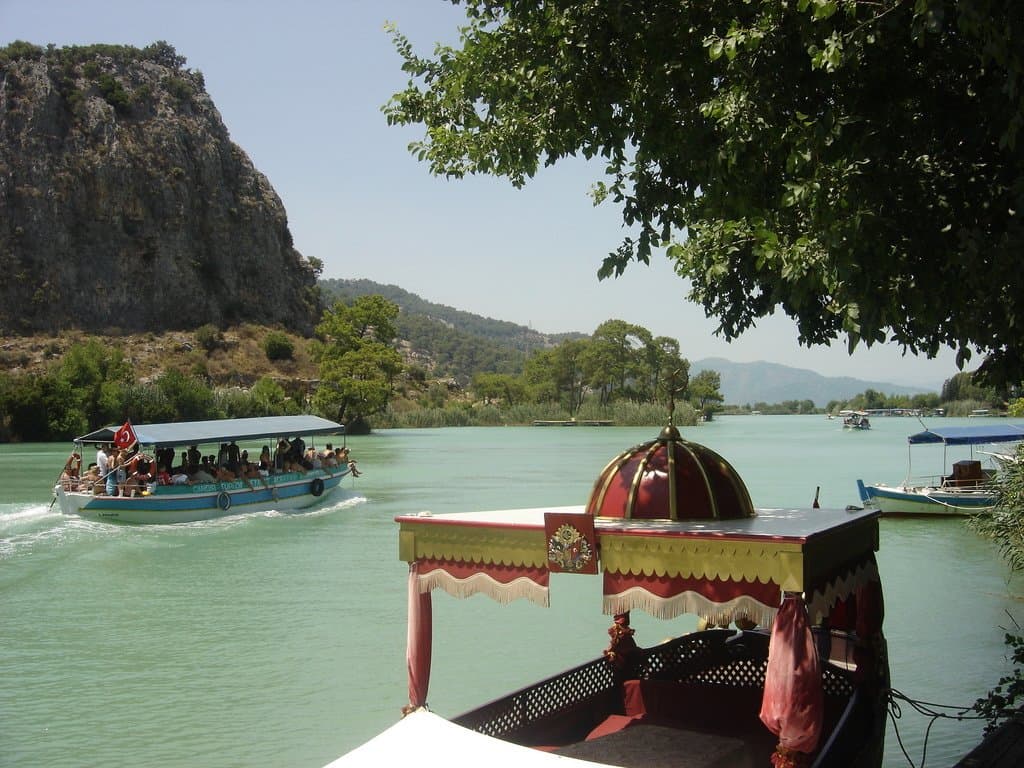 Decorated tour boat cruising a green river past forested hills