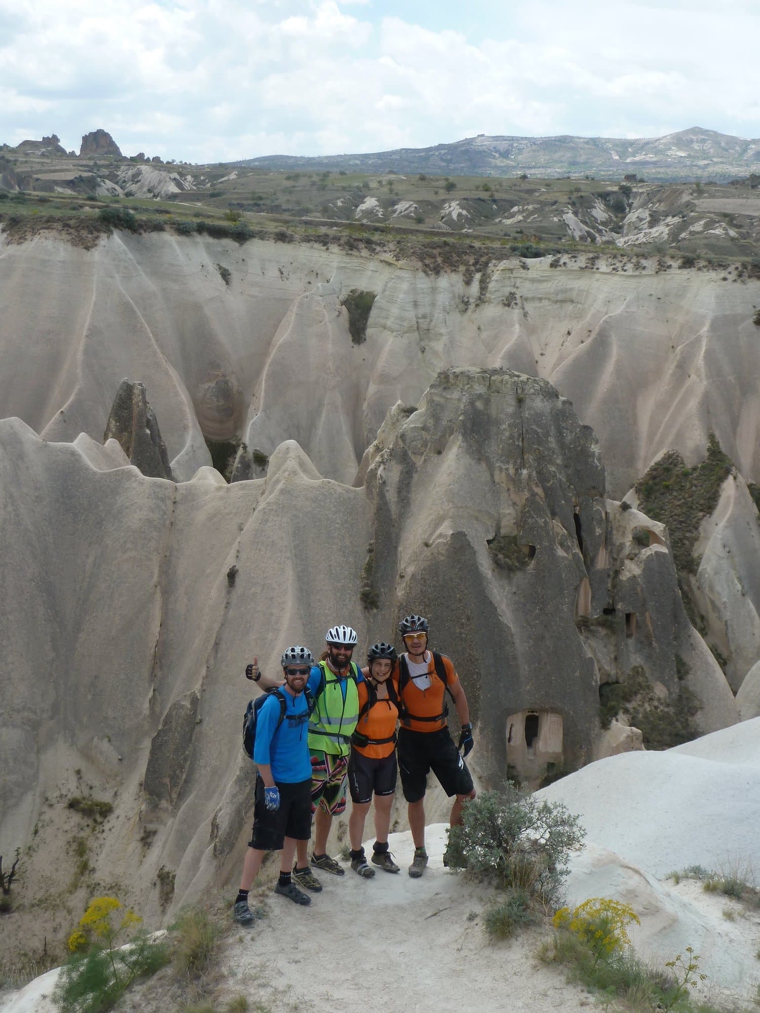 Group of cyclists posing among white rock formations in a Cappadocia canyon