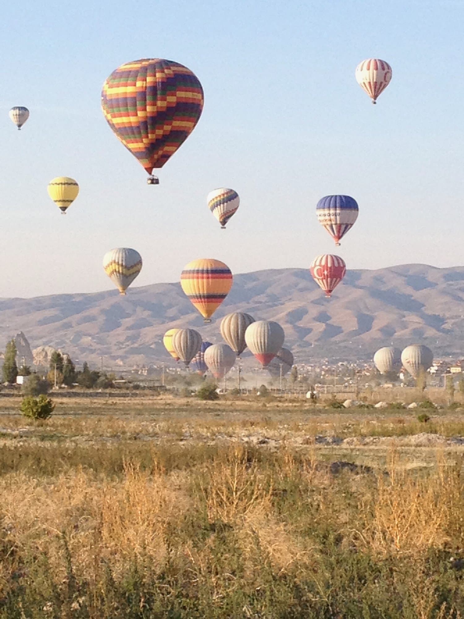 Hot air balloons rising over the Cappadocia landscape at sunrise