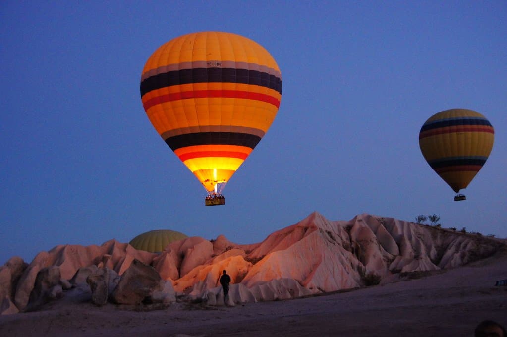 Hot air balloons rising at dawn over rock formations in Cappadocia
