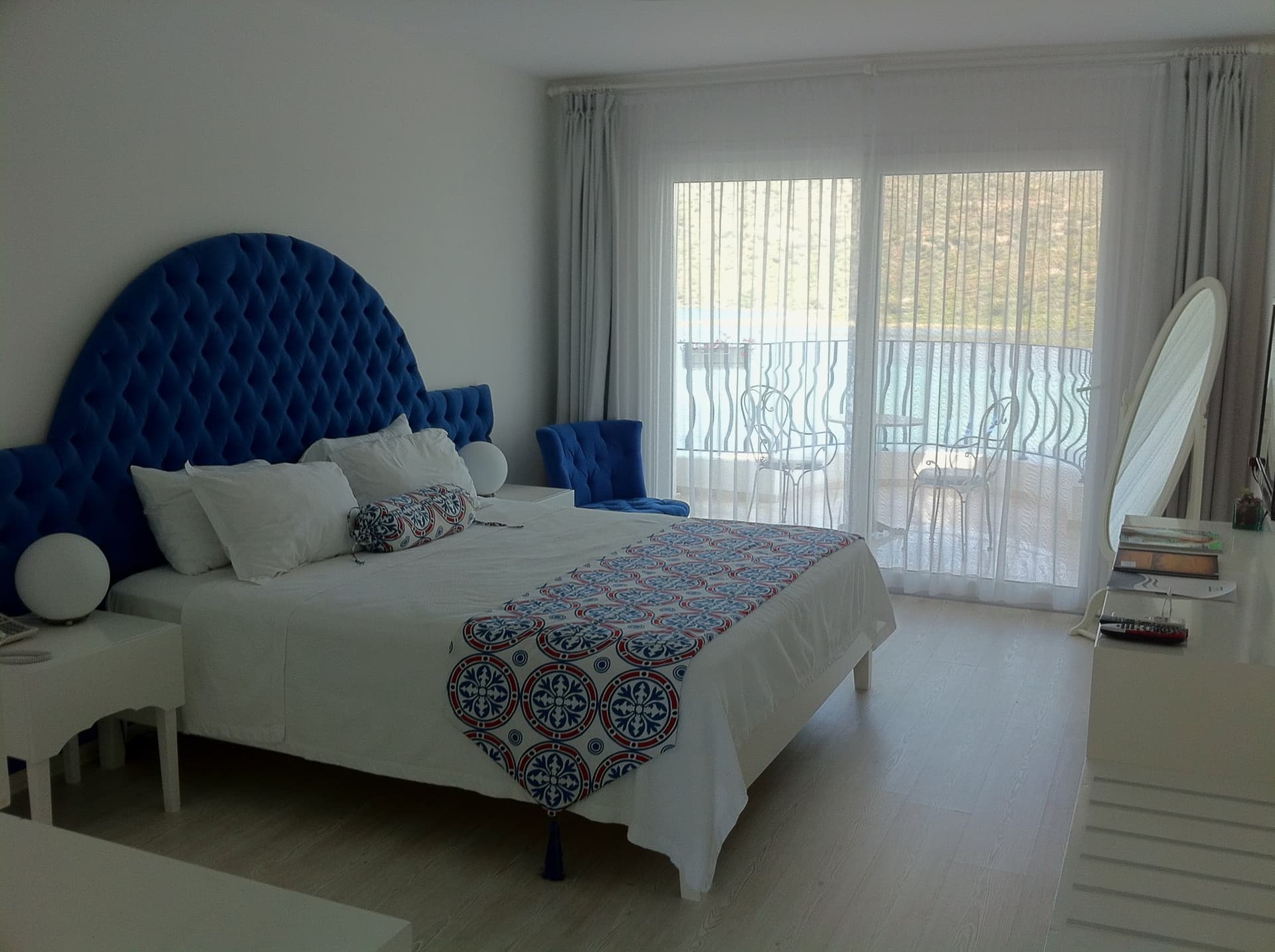 Hotel bedroom with a blue upholstered headboard and a sea-view balcony