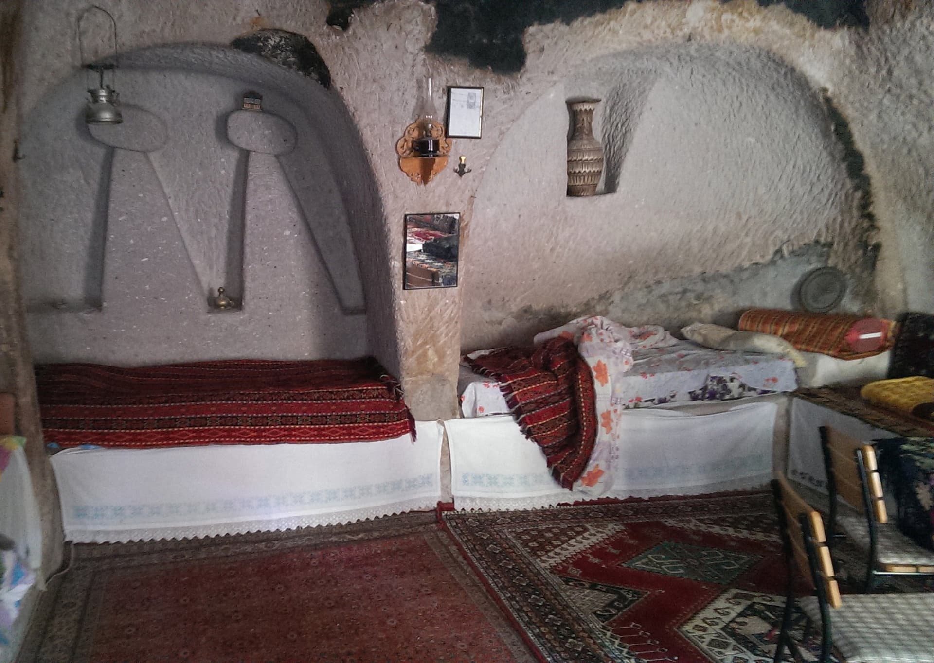 Interior of a cave room with carved stone alcoves and traditional bedding