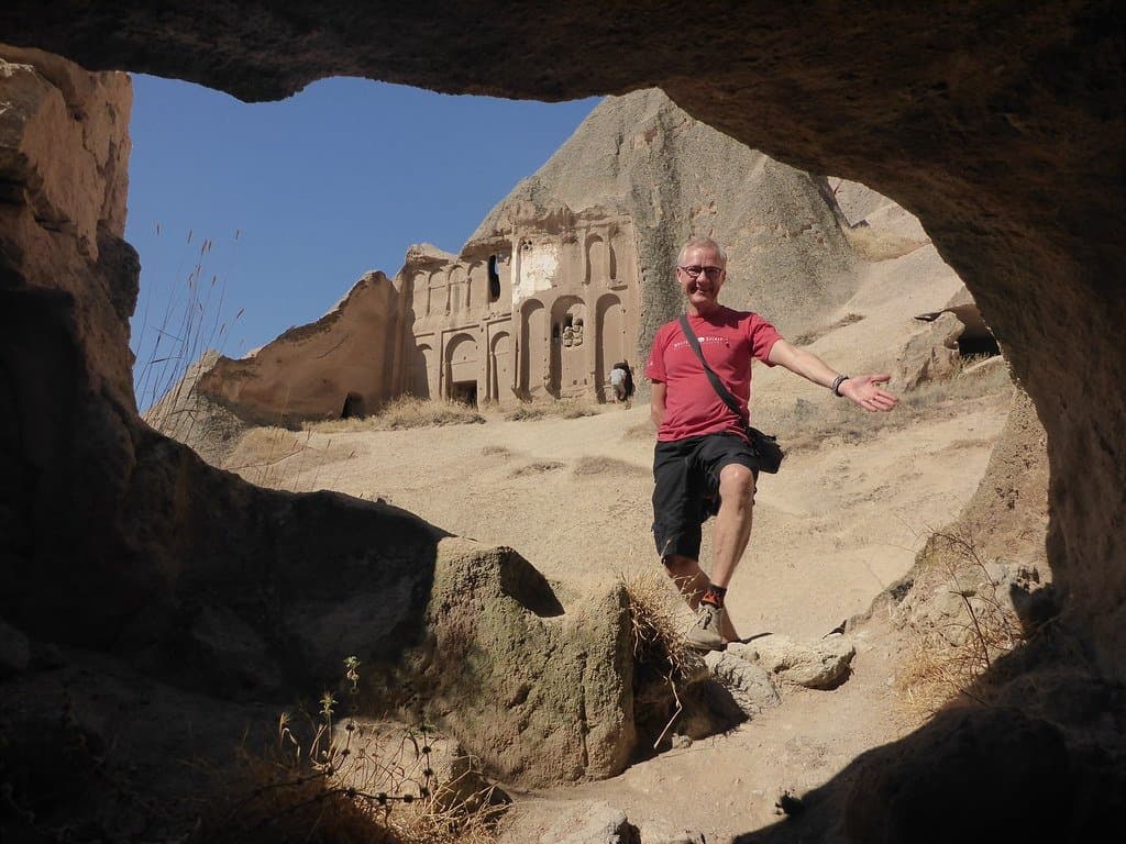 Man standing at the entrance of a rock-carved cave dwelling in Cappadocia