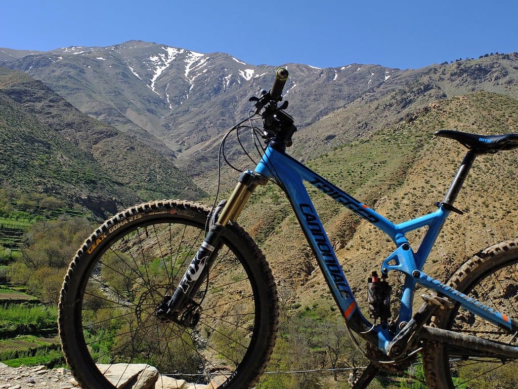 Mountain bike in the foreground with snow-capped Atlas Mountains peaks behind, Morocco