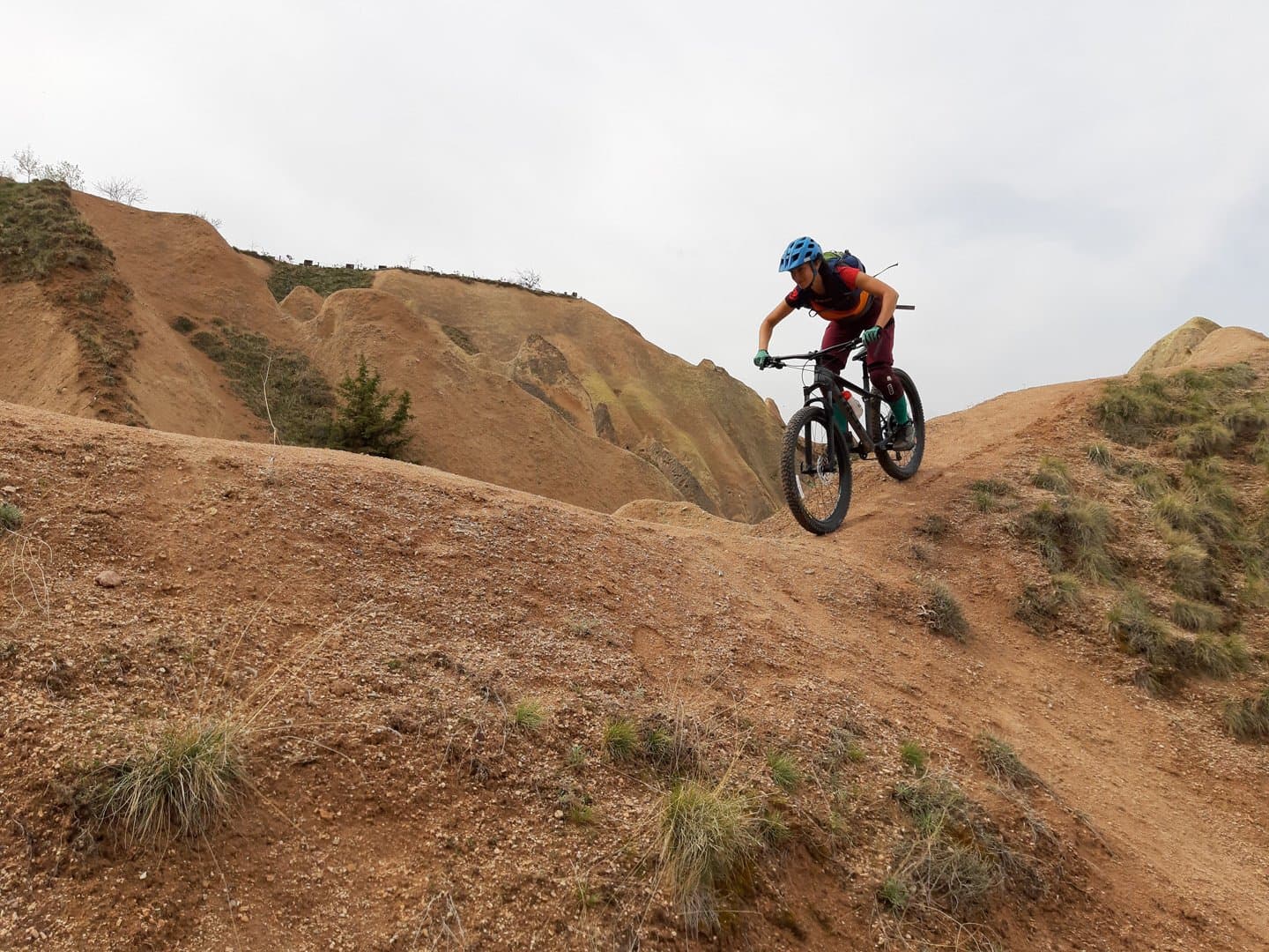Mountain biker descending a steep red dirt slope in Cappadocia