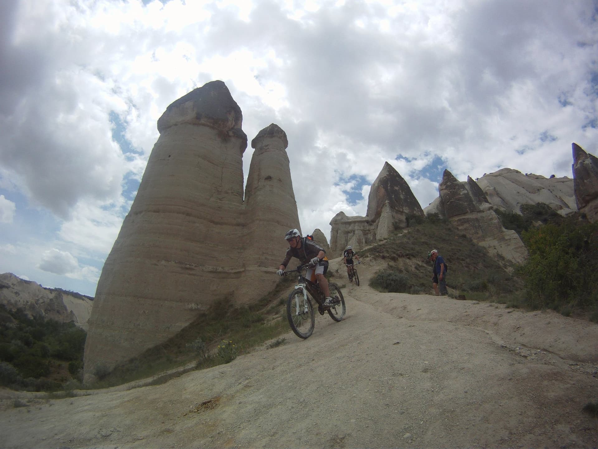 Mountain biker riding past tall fairy chimney rock pinnacles in Cappadocia