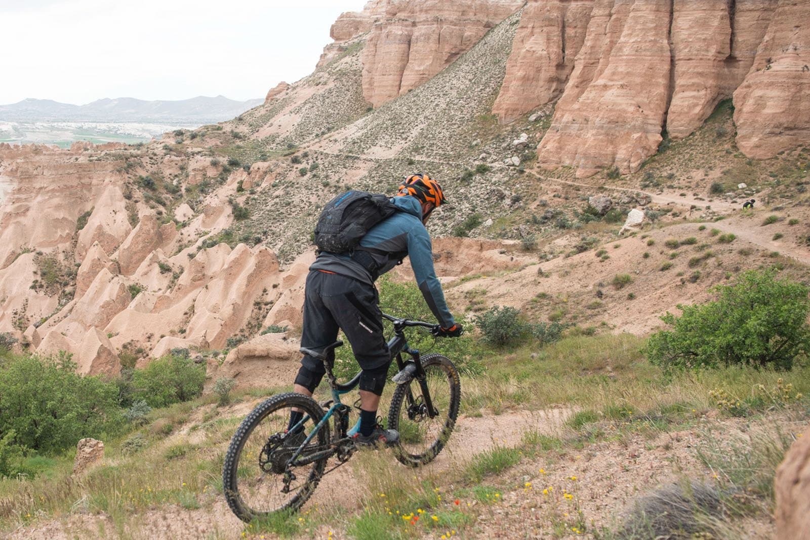 Mountain biker riding down a slope of pink rock formations in Cappadocia