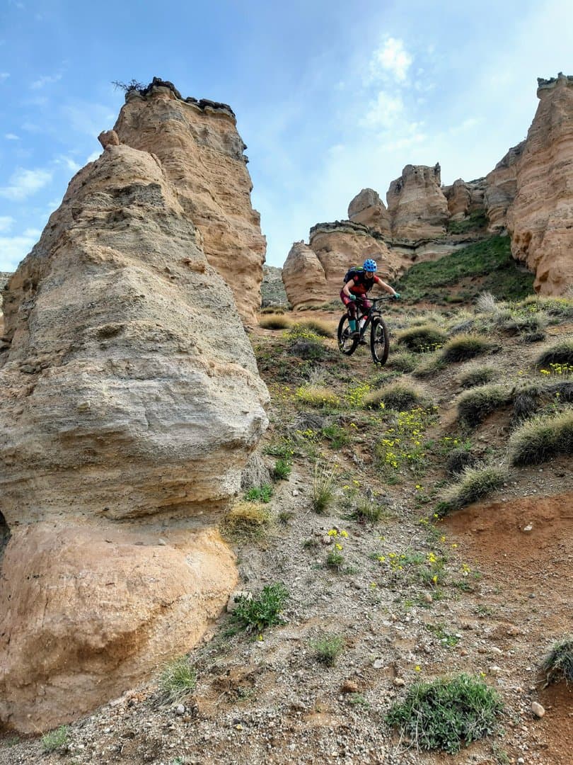 Mountain biker riding a trail beside a tall eroded rock pillar in Cappadocia