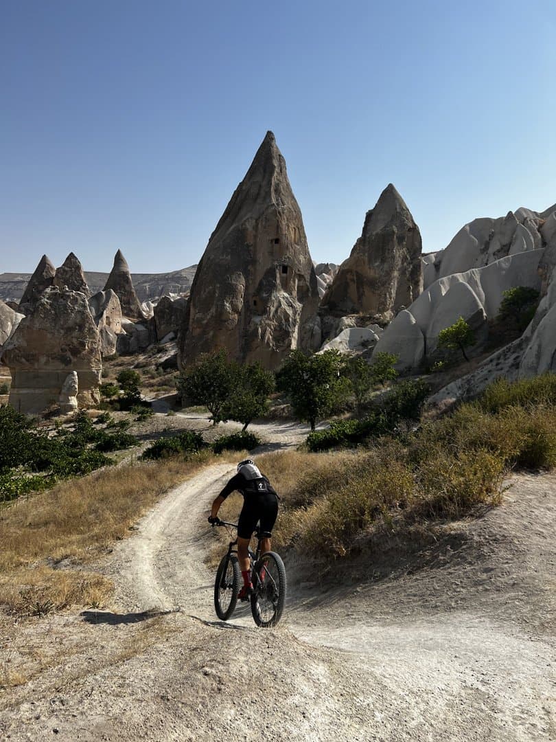 Mountain biker riding a trail past tall fairy chimney rock formations in Cappadocia