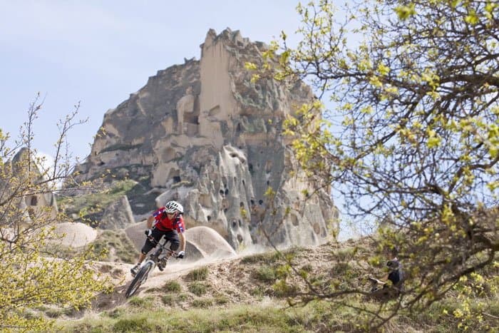 Mountain biker on a spring trail below the cave-riddled rock castle of Uchisar in Cappadocia