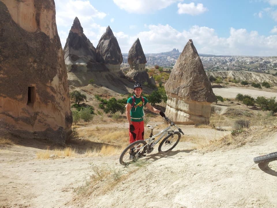 Mountain biker standing beside towering fairy chimney rock formations in Cappadocia