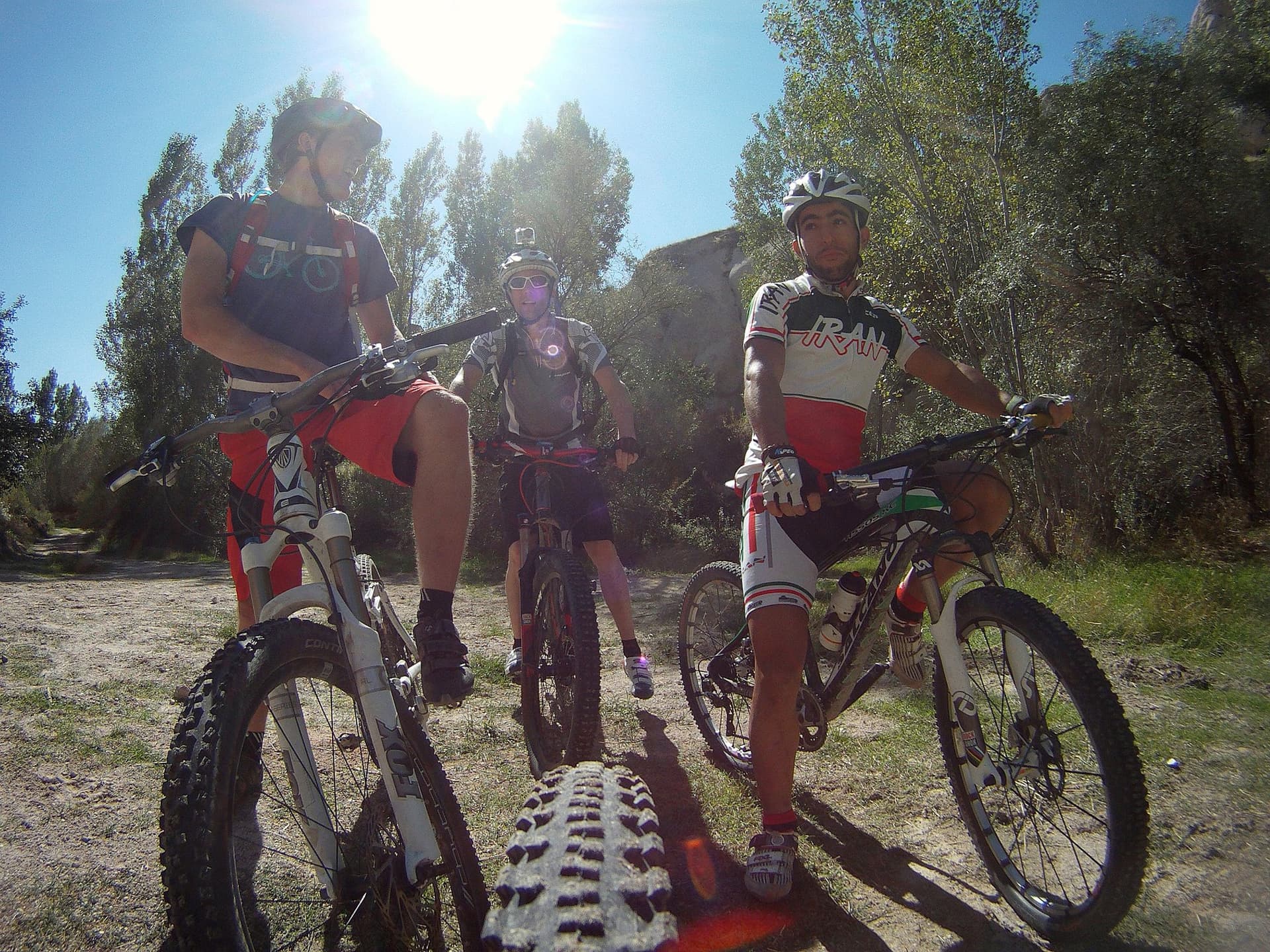 Three mountain bikers with their bikes backlit by the sun in Cappadocia