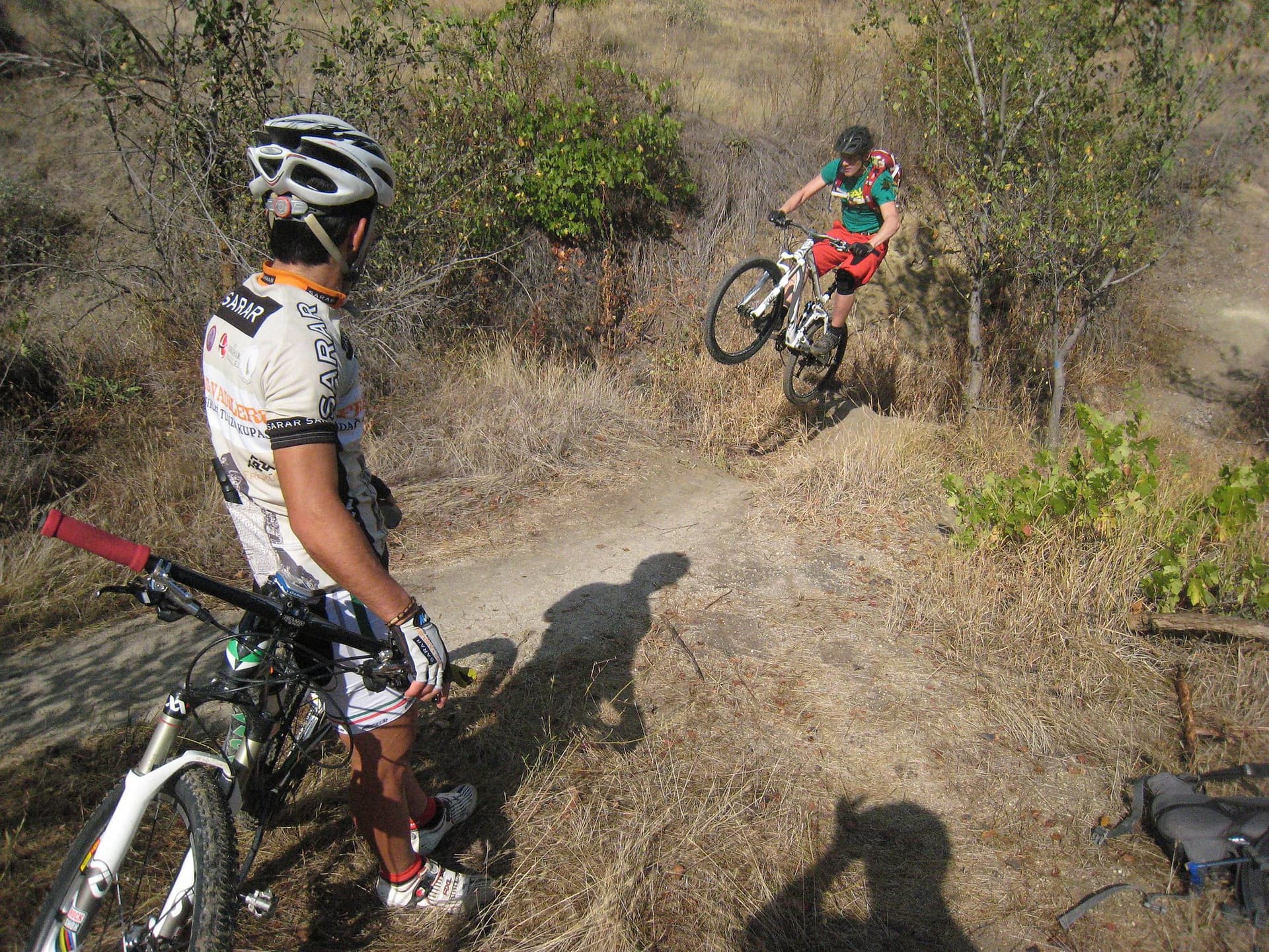 Mountain bikers riding a dusty singletrack trail through scrub in Cappadocia