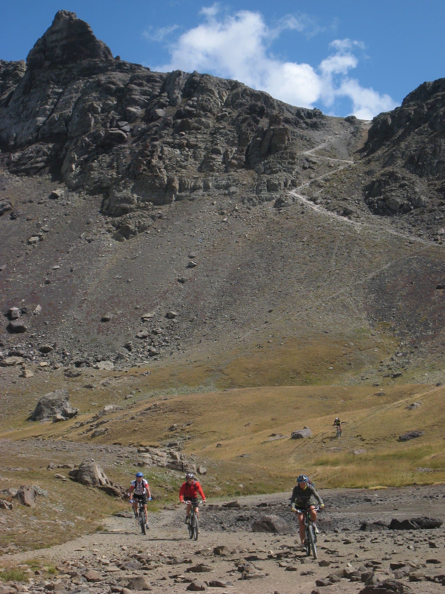 Mountain bikers riding a rocky trail below a rugged peak in the Kackar Mountains