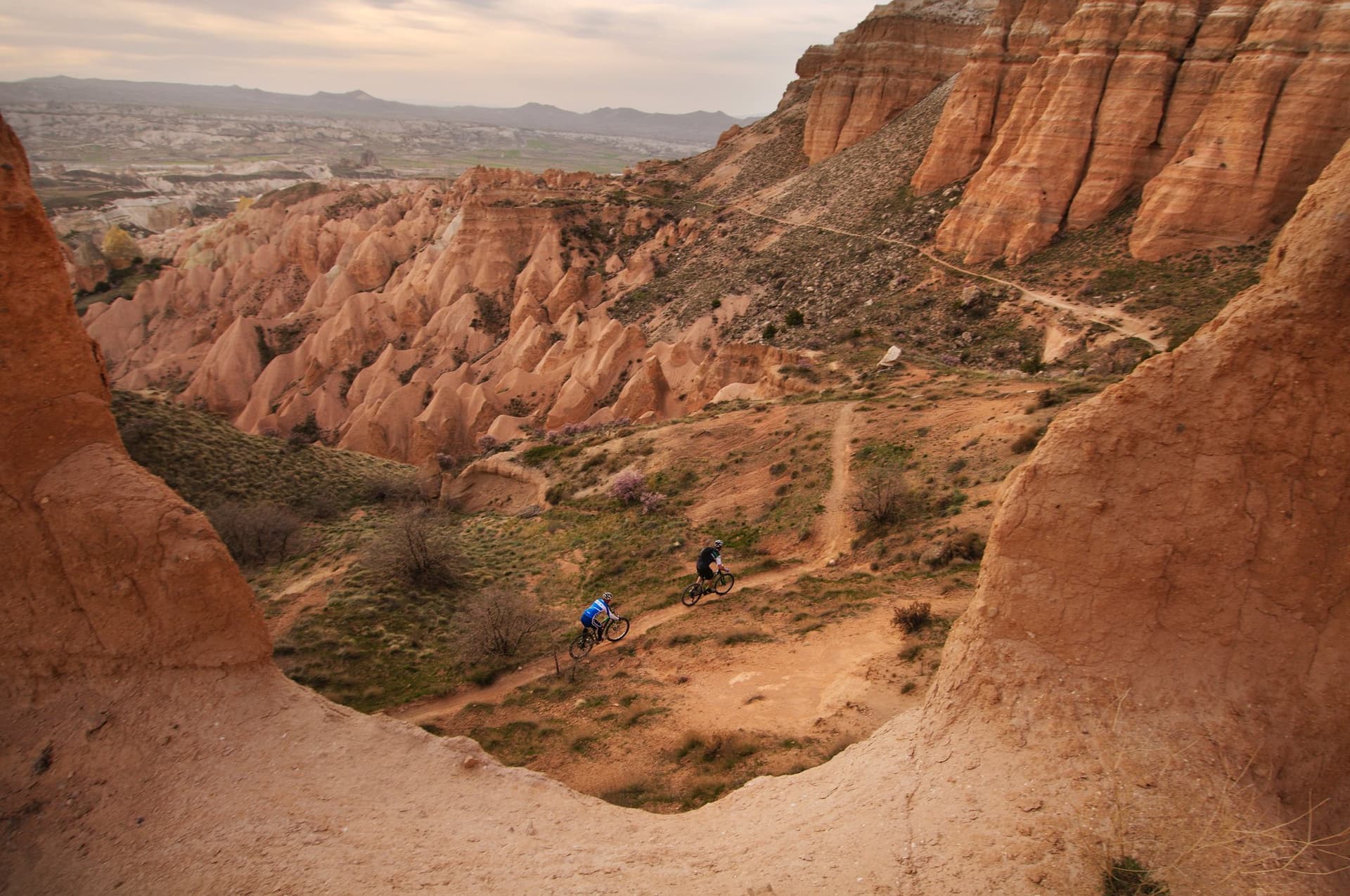 Mountain bikers riding a trail through a red rock canyon in Cappadocia