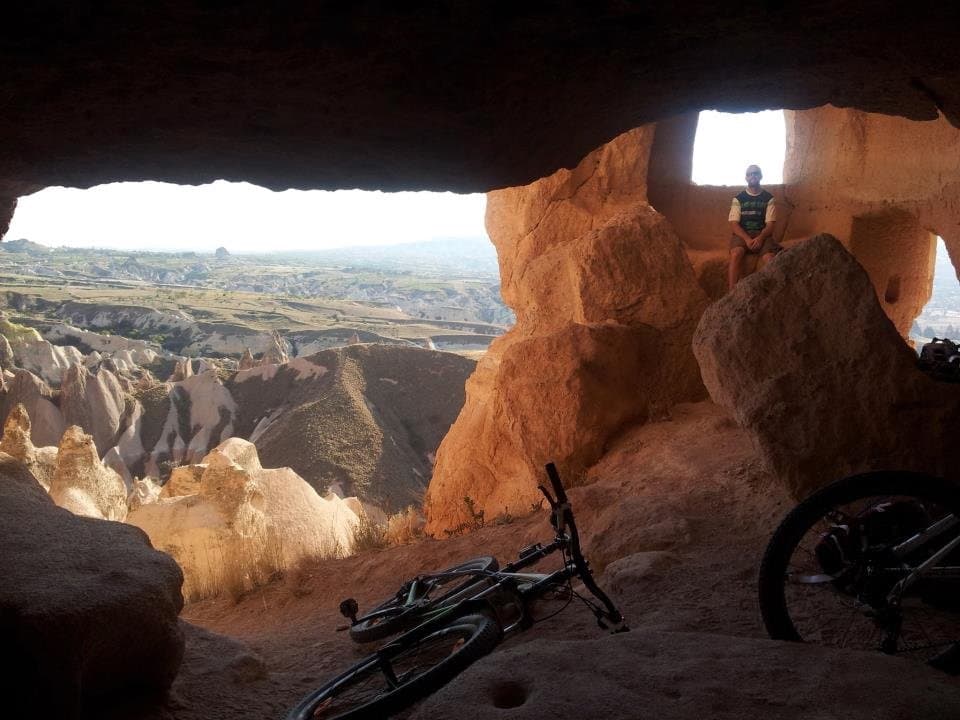 Mountain bikes parked inside a rock-carved cave overlooking a Cappadocia valley