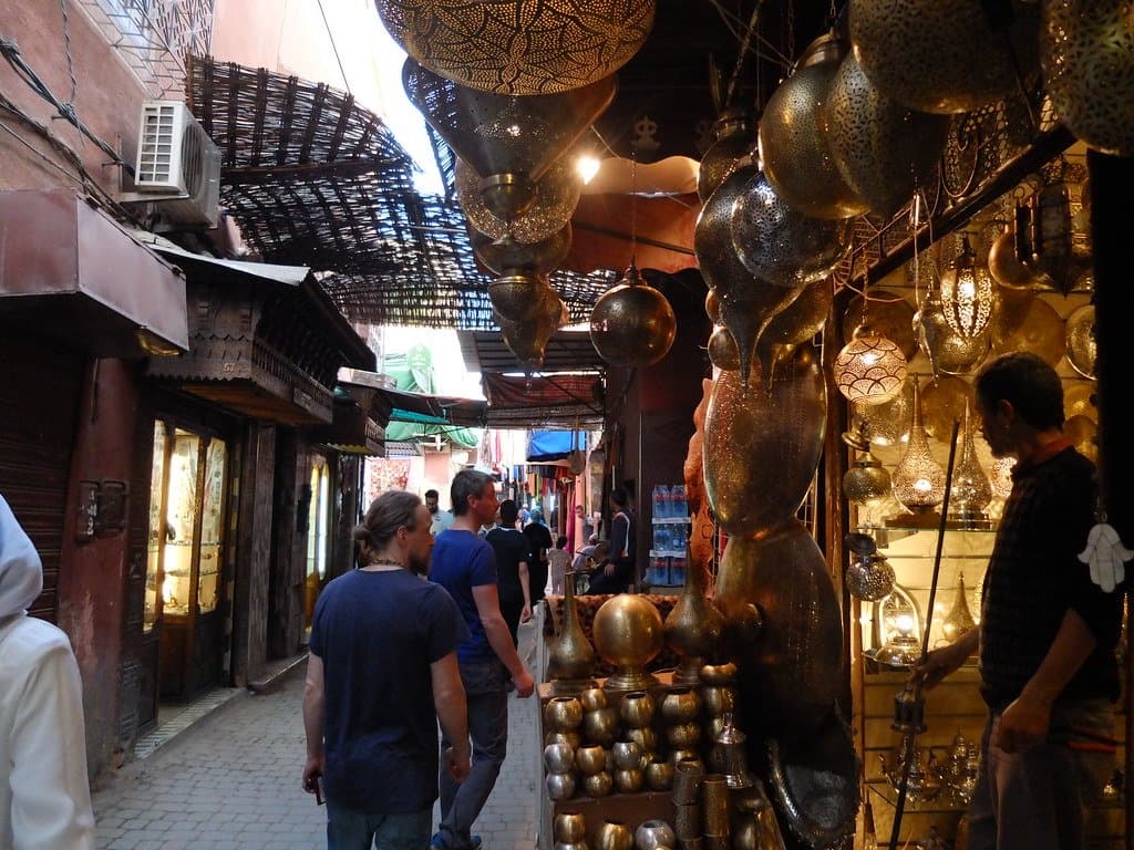 Narrow souk alley hung with ornate lanterns and lined with shoppers