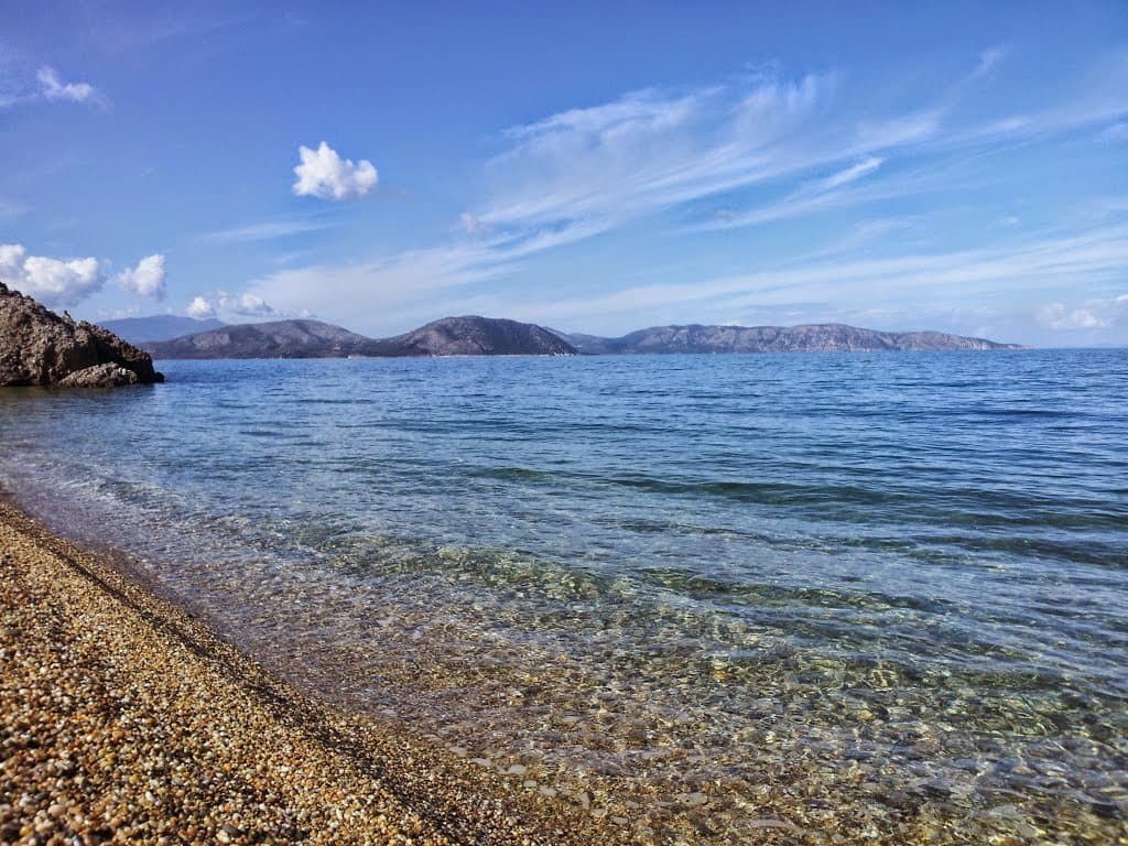 Pebble beach and calm sea dotted with small islands on the Aegean coast