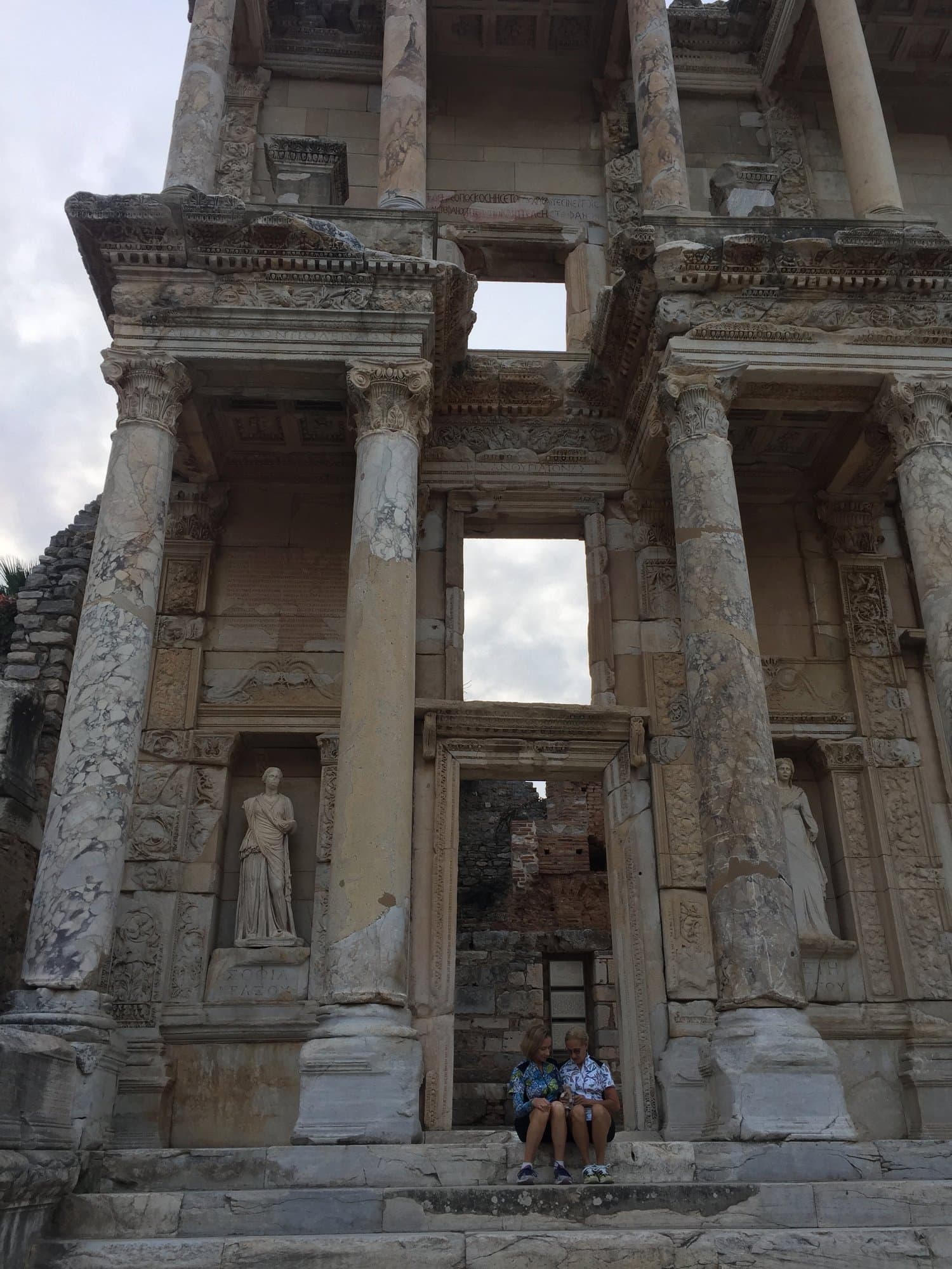 Person sitting on the steps below the Library of Celsus at Ephesus