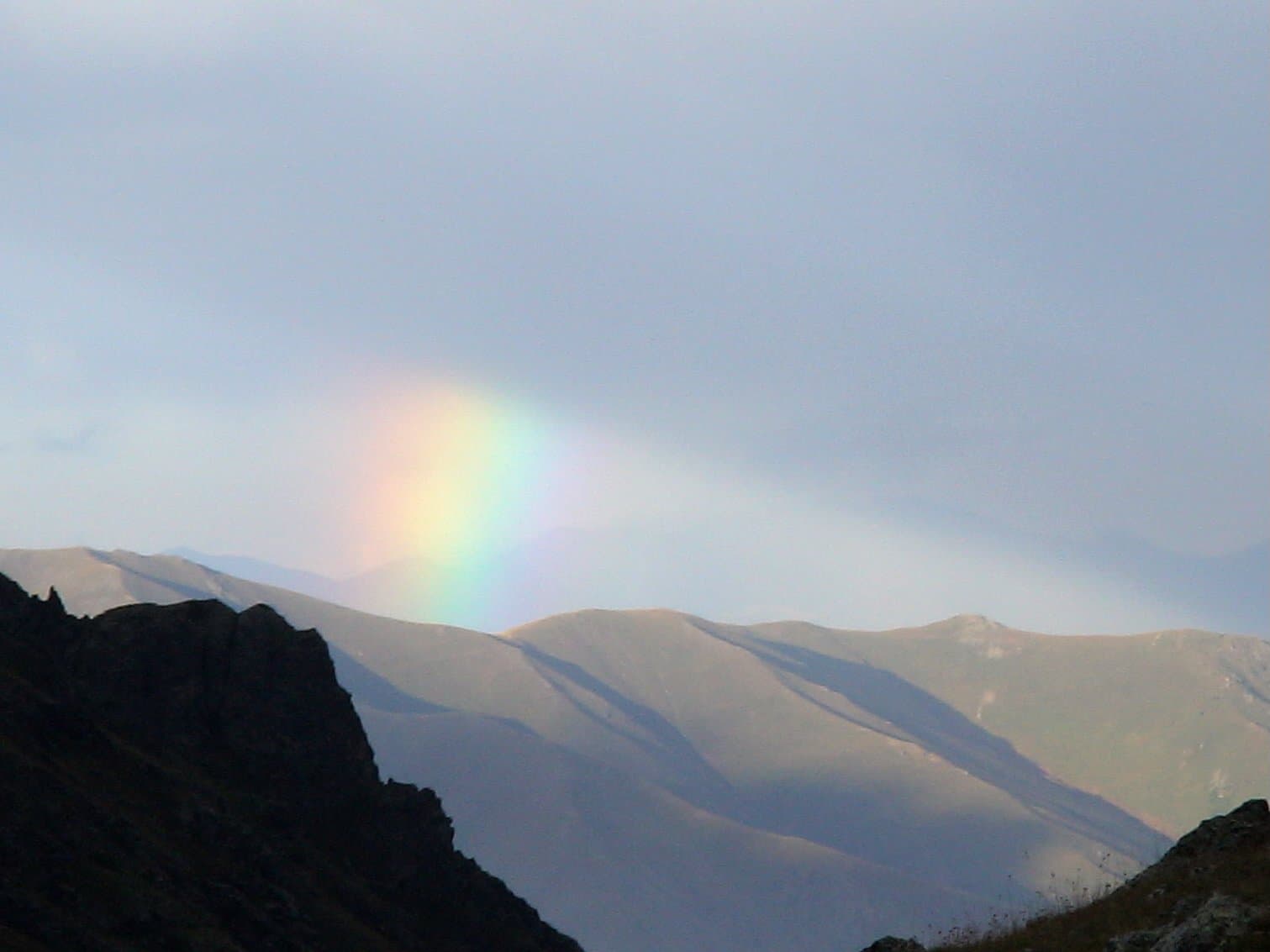 Rainbow arching over dark mountain ridges under a grey sky in the Kackar Mountains