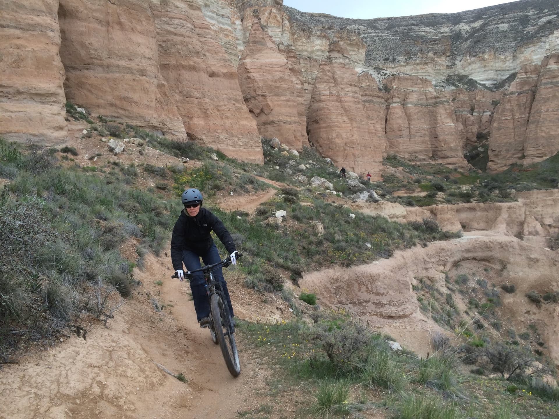 Rider on singletrack beneath the layered cliffs of Cappadocia's Red Valley