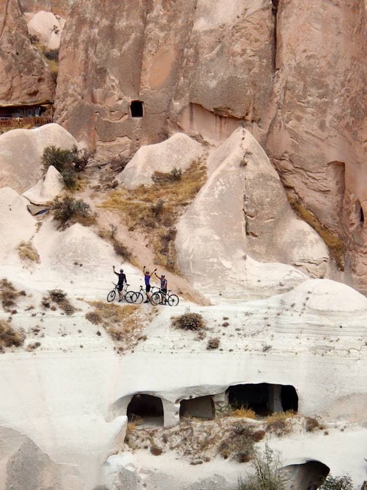 Riders gathered on a white rock ledge above carved cave dwellings in Cappadocia