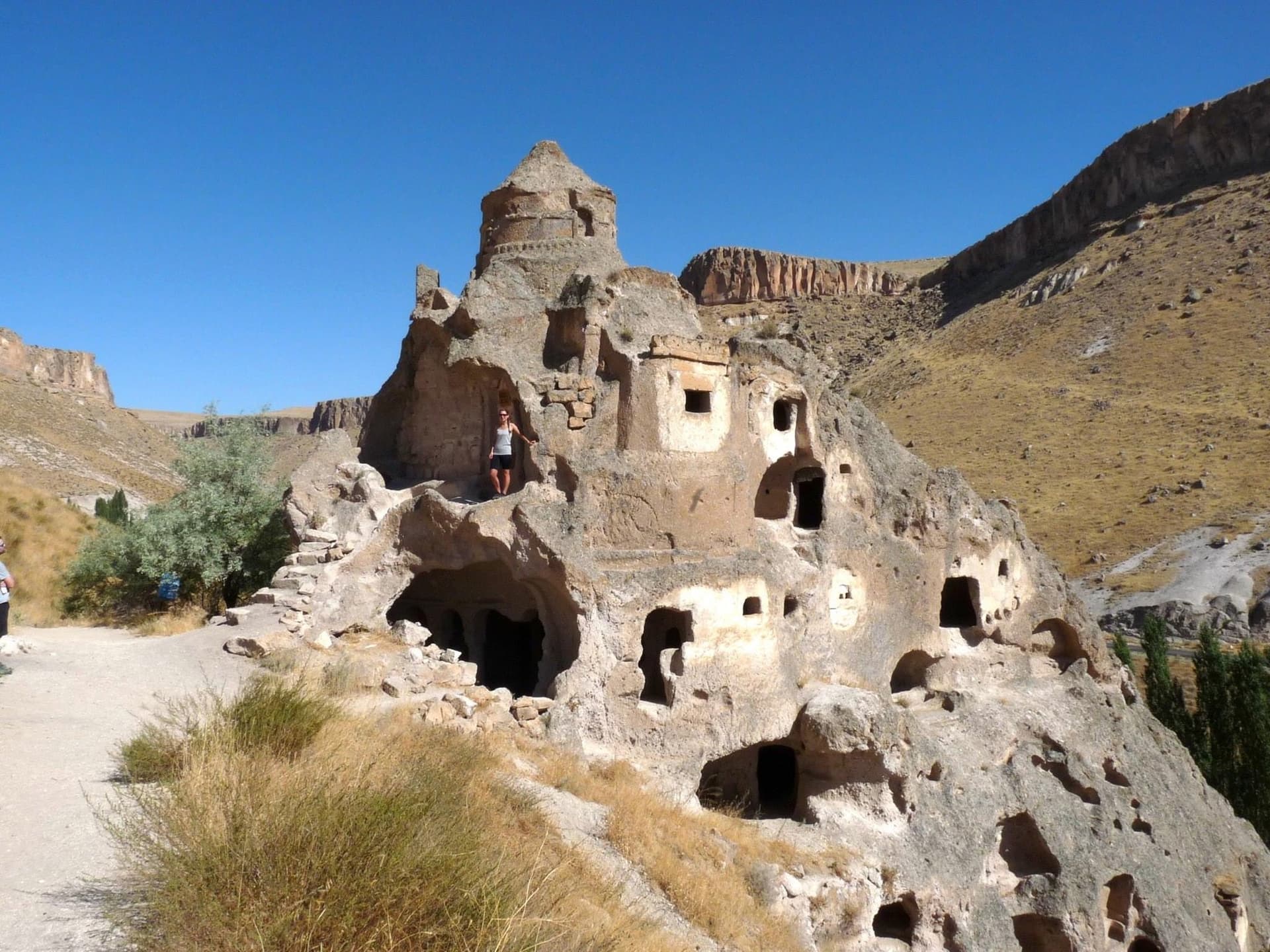 Rock-cut fortress dwelling with carved windows rising from a Cappadocia hillside