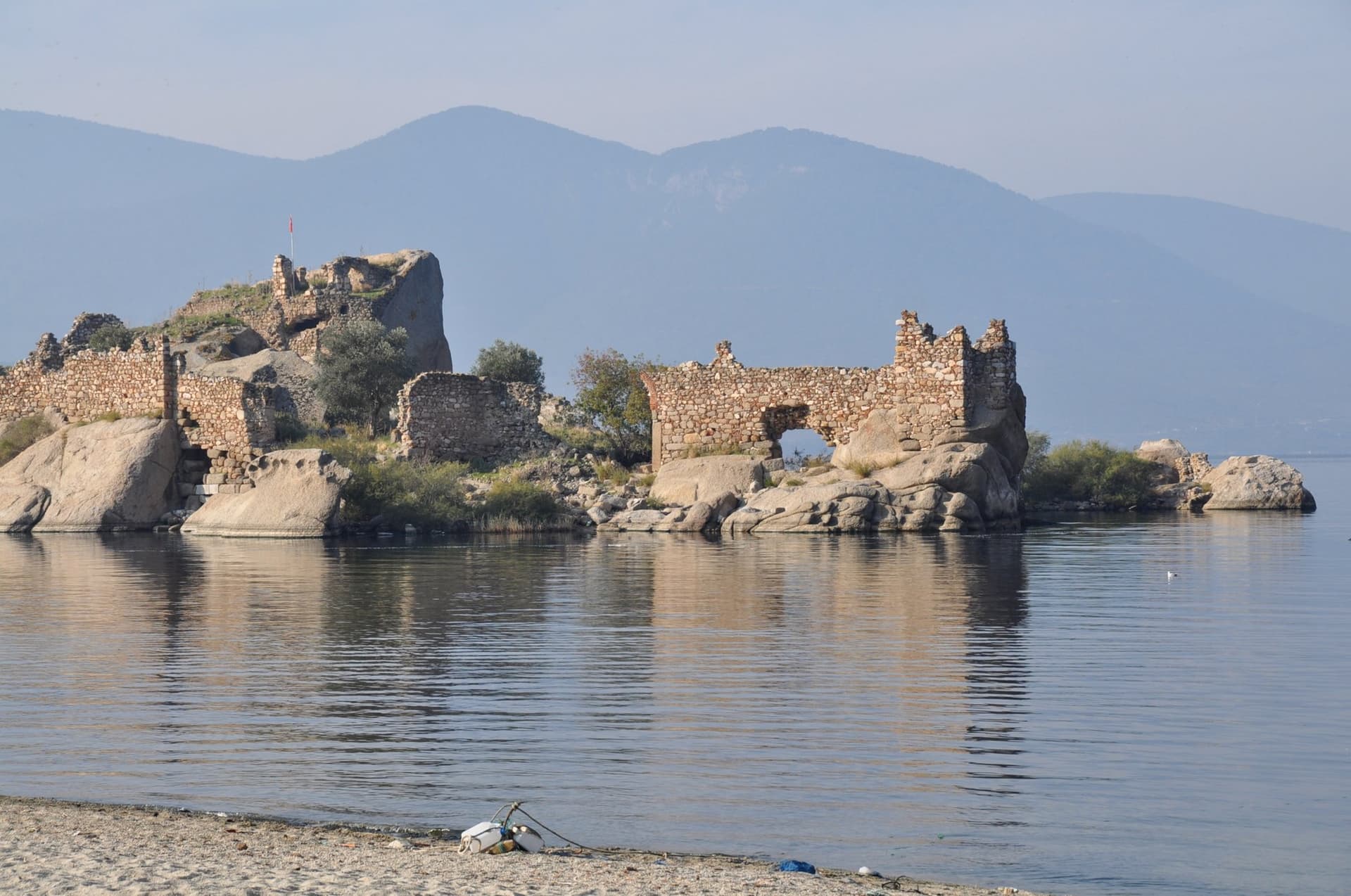 Ruined stone fortress on a small island in a calm bay on the Aegean coast