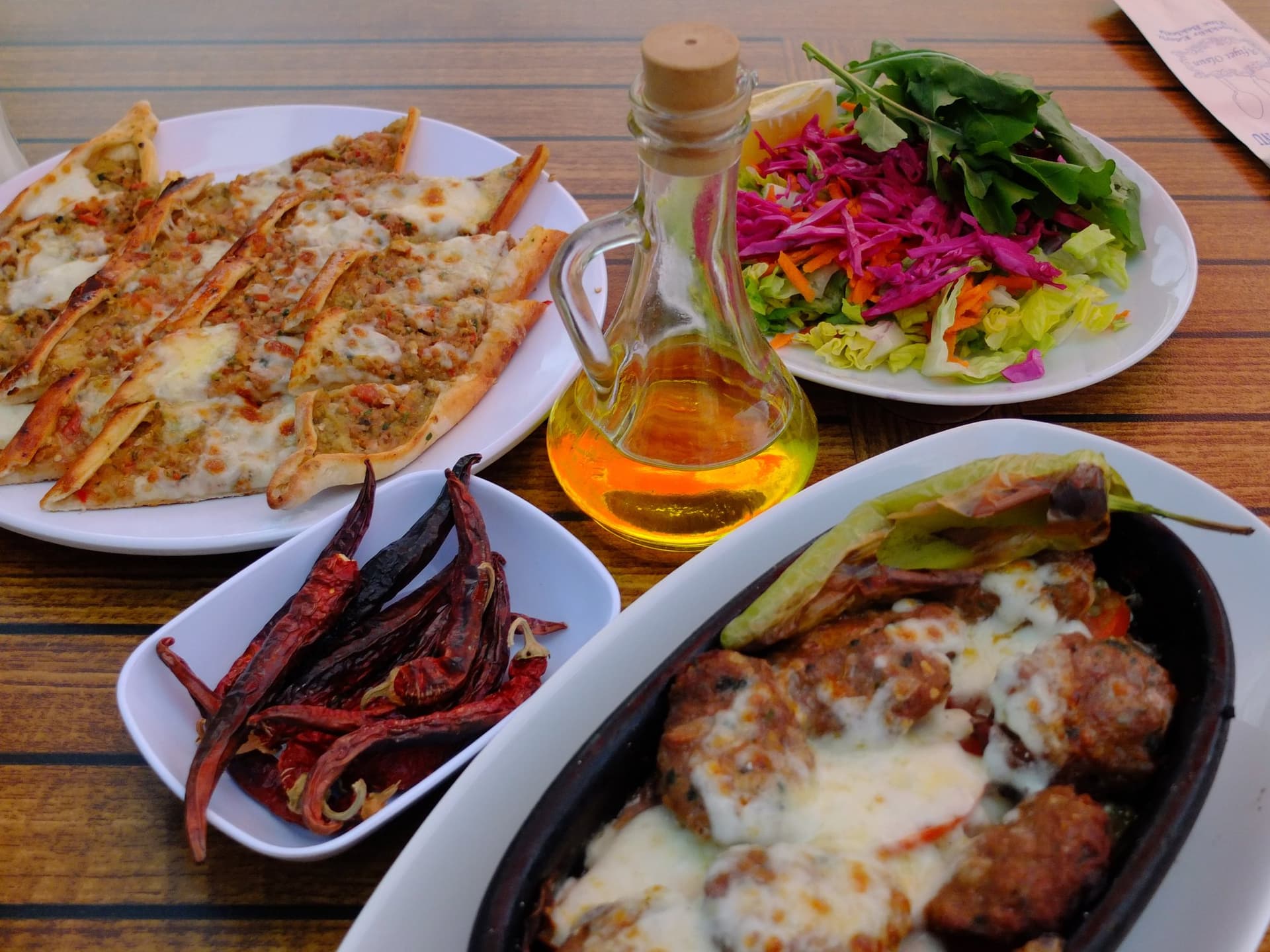 Spread of Turkish pide, grilled meatballs, dried peppers and fresh salad on a table