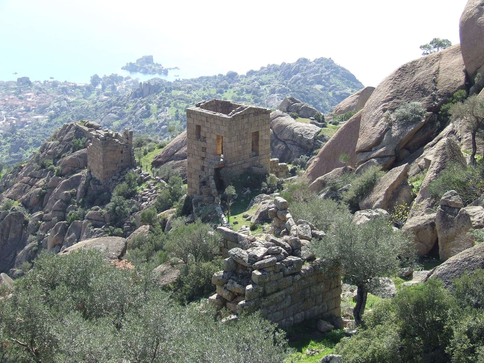 Stone fort ruins nestled among huge granite boulders and olive trees