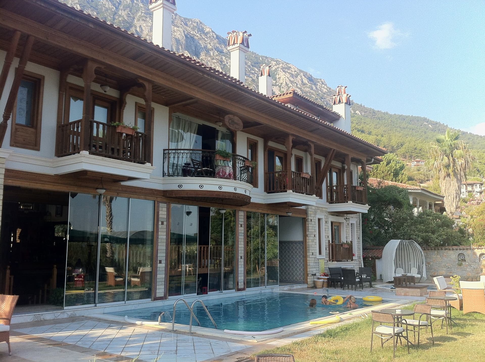 Stone and timber hotel building with a pool beneath mountain slopes