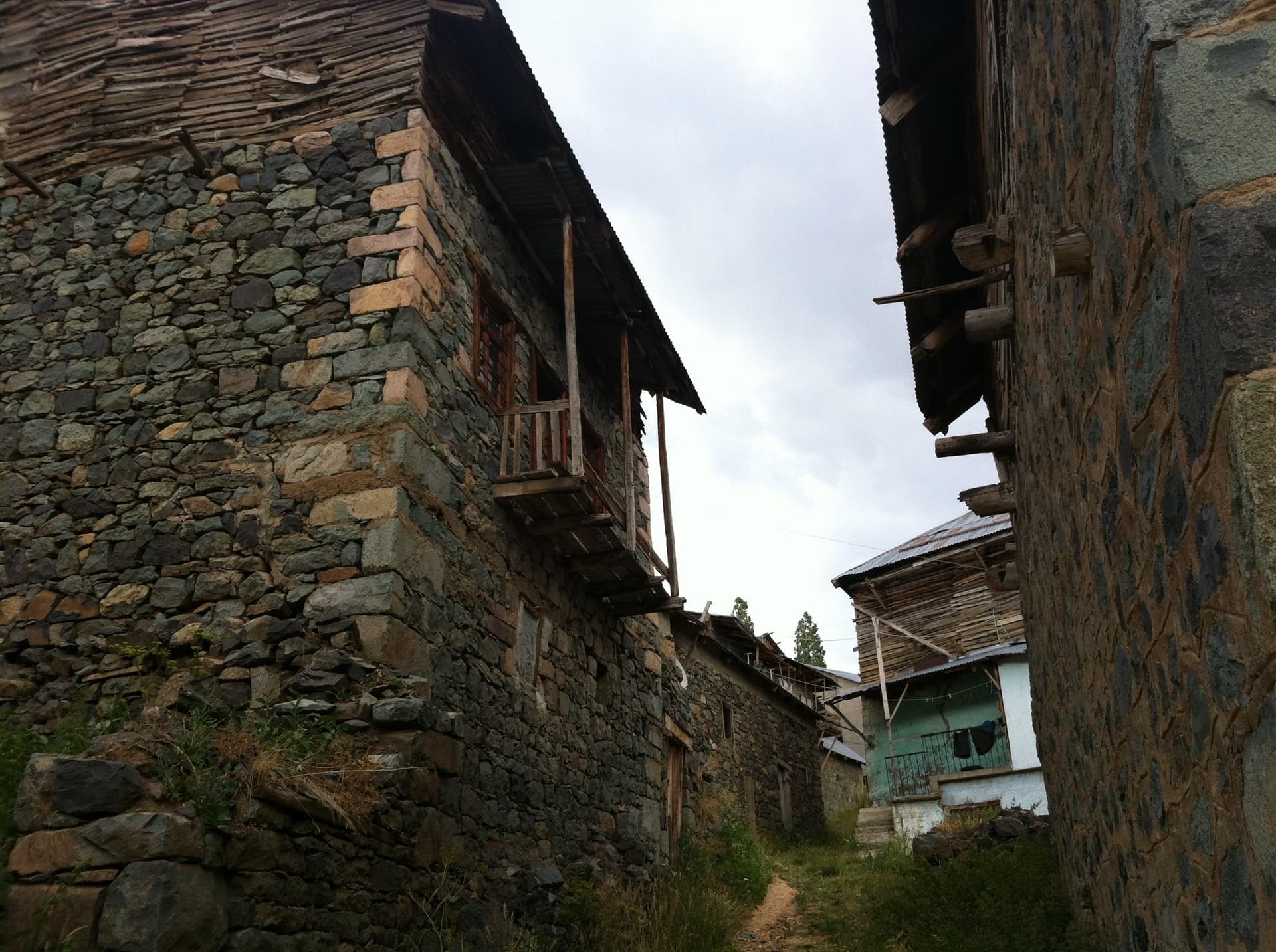 Stone village house with a wooden balcony along a narrow lane in the Kackar Mountains