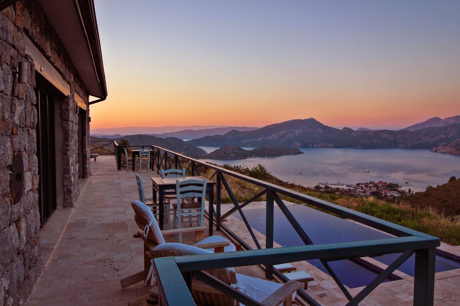 Terrace overlooking a bay at sunset beside a stone hotel building